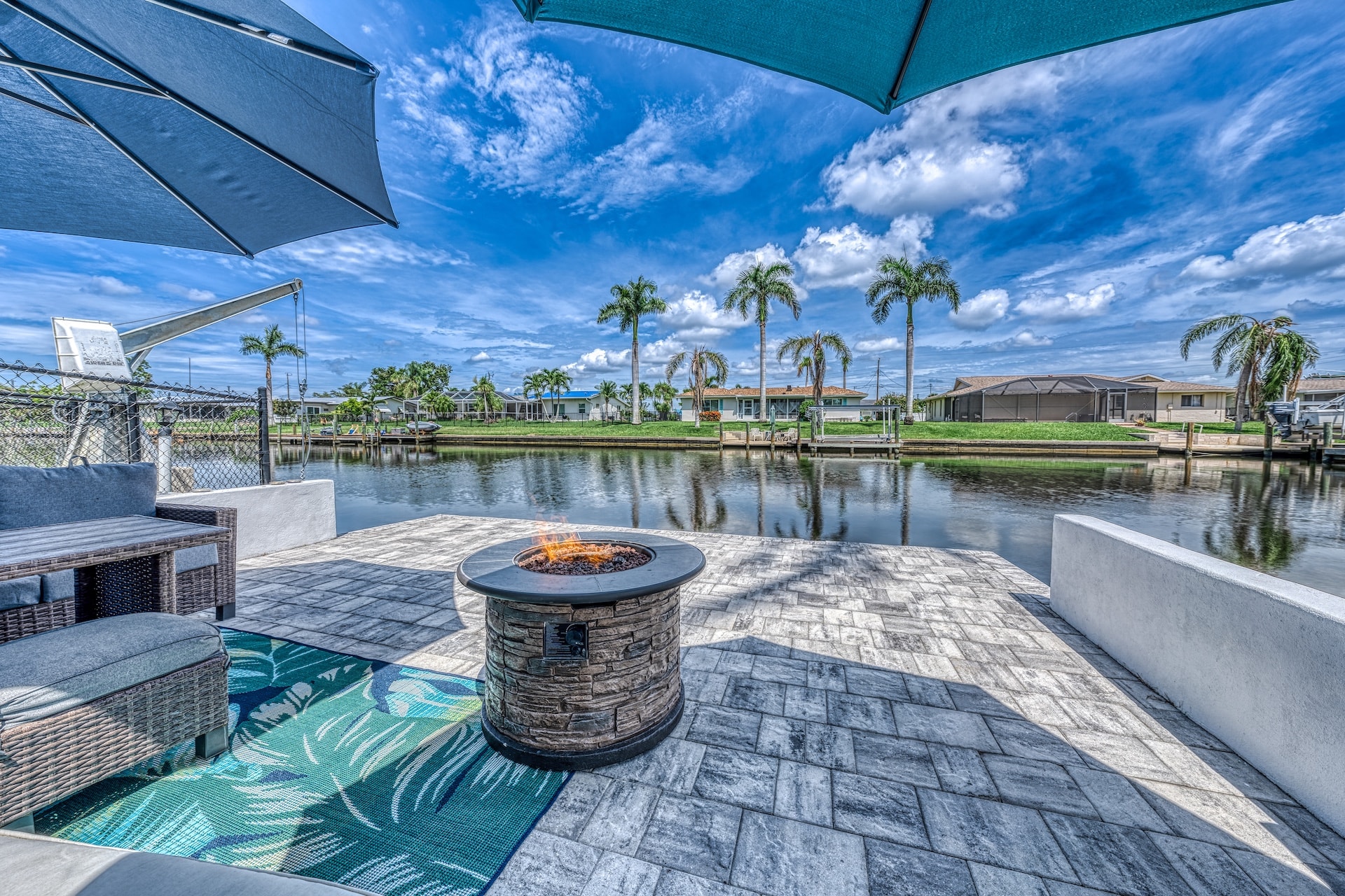 Waterfront patio with fire pit and palm trees